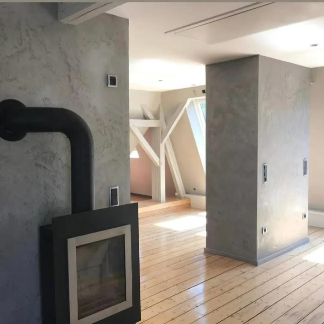 Wandgestaltung mit Spachteltechnik Dachgeschoss - Ansprechende Spachteltechnik an Wänden in einem modernen Dachgeschoss mit Holzbalken und Kaminofen.