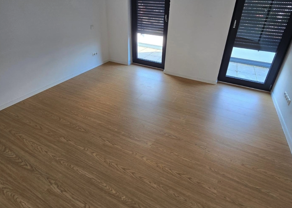 Neues Laminat in modernem Wohnraum - Verlegung von neuem Laminatboden in Holzoptik in einem frisch renovierten Innenraum mit weißen Wänden.